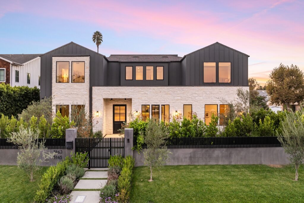 Modern luxury home exterior at sunset with lush garden and clear sky, showcasing contemporary architecture.